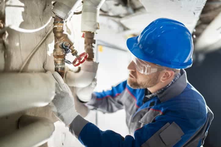 Commercial plumber working on pipes